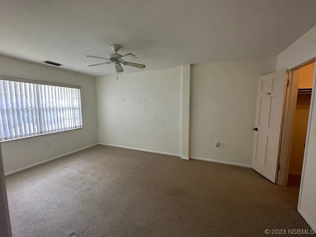 an empty room with windows and fan