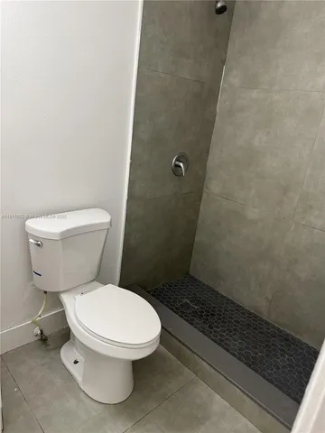 a white toilet sitting next to a shower