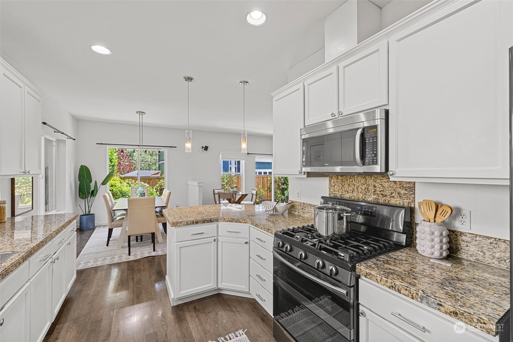 23825 17th Avenue West Bothell, WA 98021 - Photo 10 of 35 a kitchen with stainless steel appliances granite countertop a stove top oven a sink a dining table and chairs with wooden floor