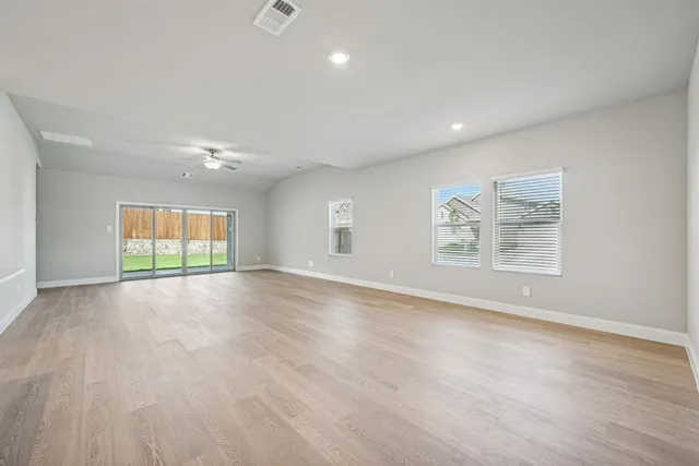 an empty room with wooden floor and windows