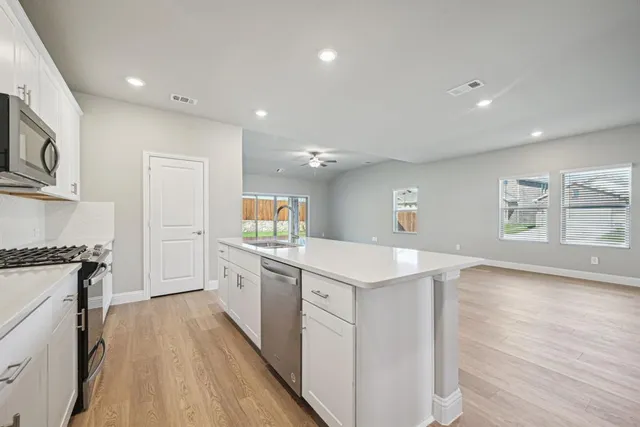 a kitchen with white cabinets appliances and wooden floor
