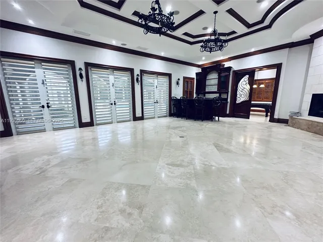 a view of an empty room with wooden floor and chandelier