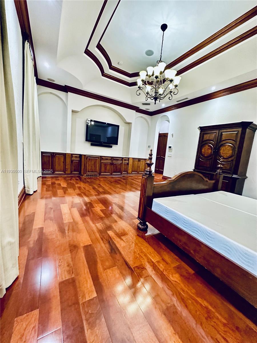 6180 Southwest 132nd Street Pinecrest, FL 33156 - Photo 45 of 75 a bedroom with a bed and a chandelier