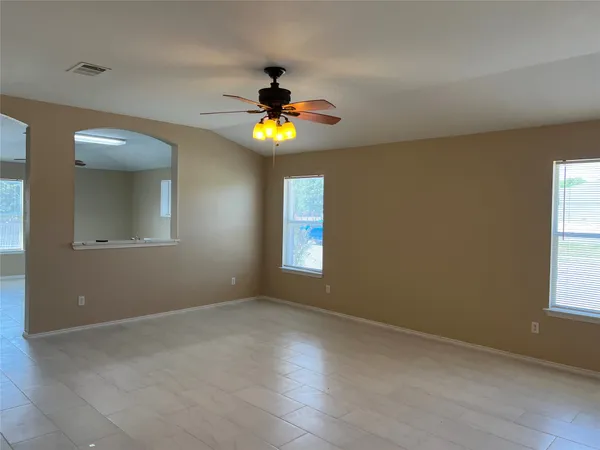 an empty room with windows and chandelier fan