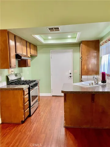 a kitchen with stainless steel appliances granite countertop a sink a stove and a wooden floors