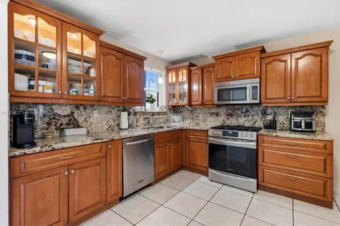 a kitchen with stainless steel appliances granite countertop wooden cabinets a stove top oven and a granite counter top