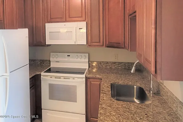 a kitchen with granite countertop a sink stove and refrigerator