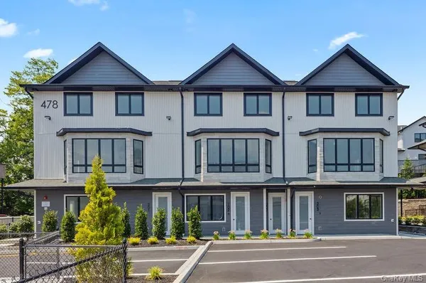 a front view of a residential apartment building with a yard and porch
