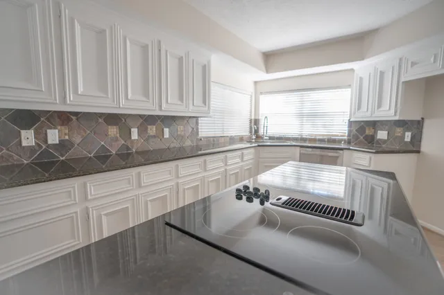 a kitchen with granite countertop white cabinets and white appliances