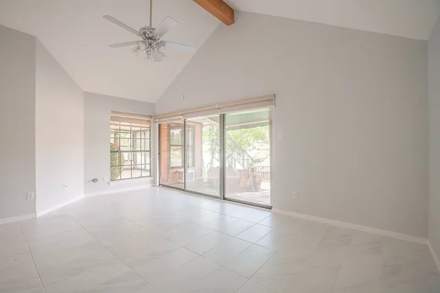 an empty room with chandelier fan and windows