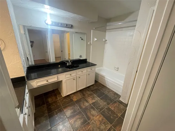 a bathroom with a granite countertop sink a mirror and a bathtub