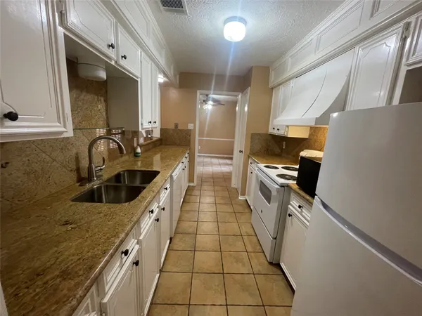 a kitchen with granite countertop a sink a counter top space stainless steel appliances and cabinets