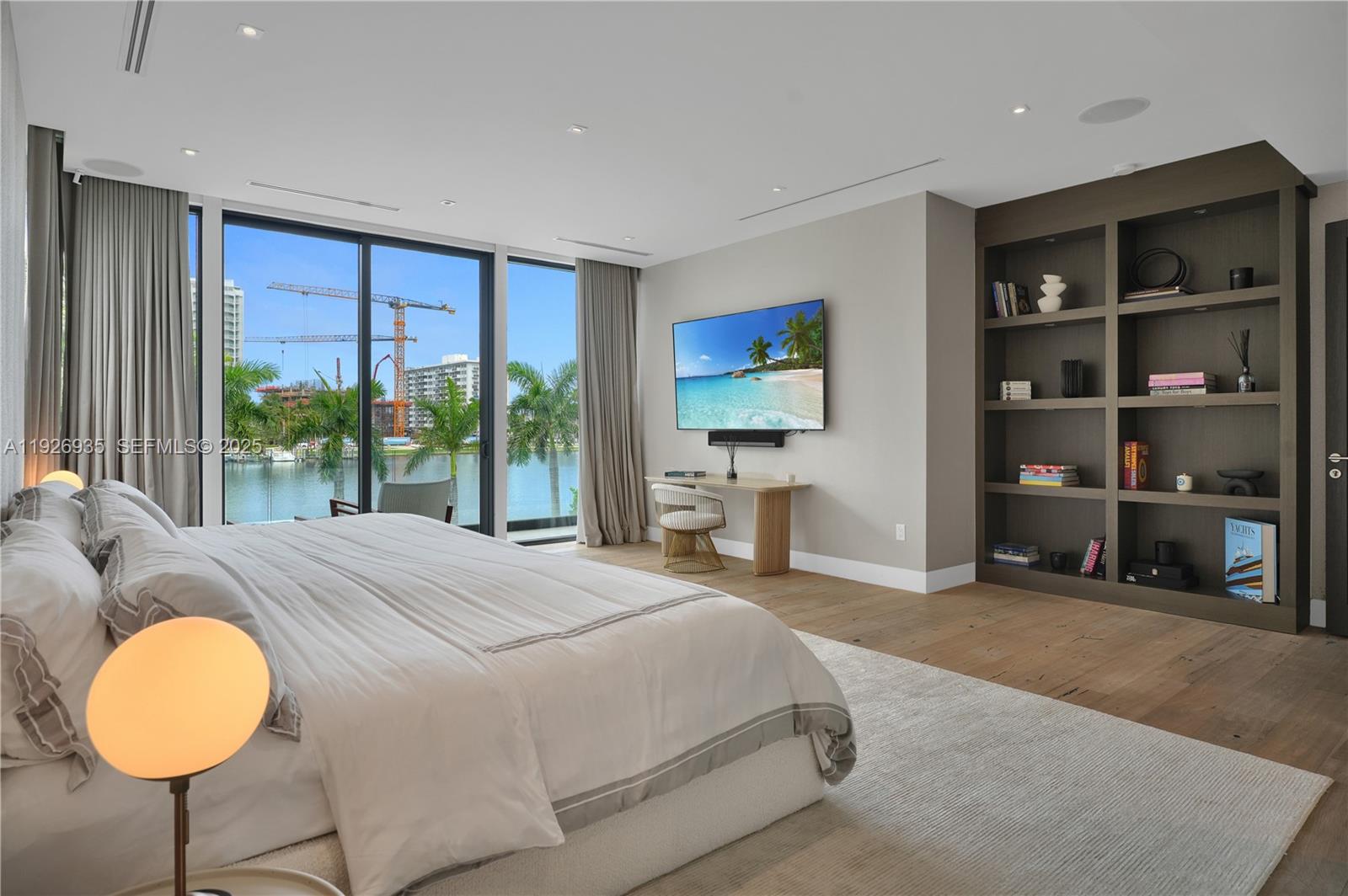 5501 Pine Tree Drive Miami Beach, FL 33140 - Photo 33 of 60 a spacious bedroom with a bed a table and a chandelier