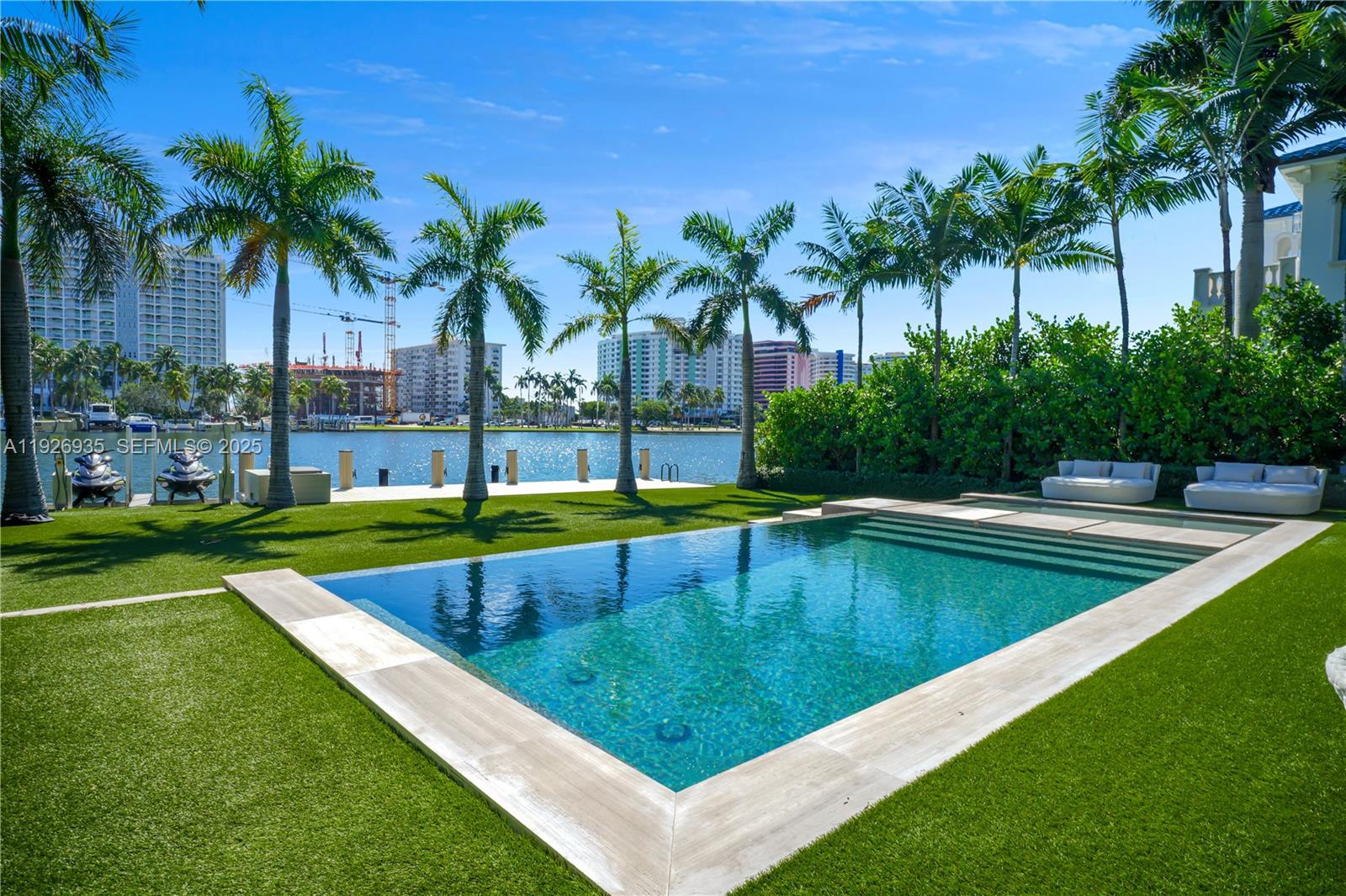 5501 Pine Tree Drive Miami Beach, FL 33140 - Photo 6 of 60 a view of a swimming pool with a lawn chairs under palm trees