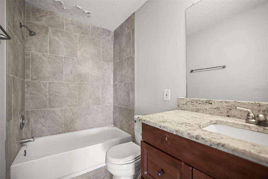 455 Alt 19, Unit 175 Palm Harbor, FL 34683 - Photo 16 of 35 a bathroom with a granite countertop bathtub shower sink vanity and toilet