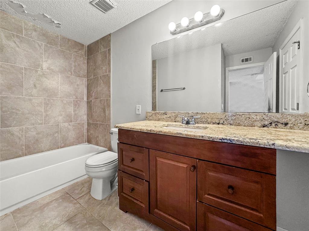455 Alt 19, Unit 175 Palm Harbor, FL 34683 - Photo 17 of 35 a bathroom with a granite countertop toilet a sink and bathtub