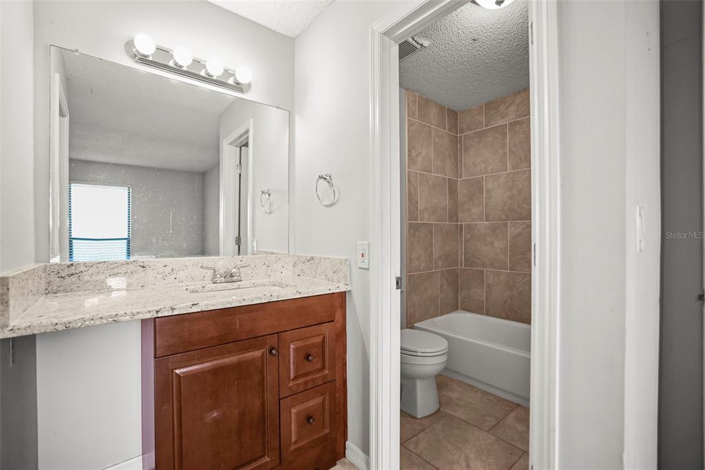 455 Alt 19, Unit 175 Palm Harbor, FL 34683 - Photo 18 of 35 a bathroom with a granite countertop sink a toilet a mirror and shower