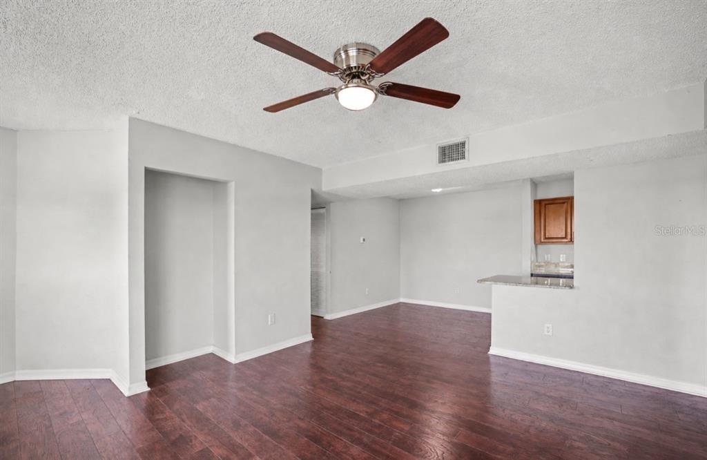 455 Alt 19, Unit 175 Palm Harbor, FL 34683 - Photo 6 of 35 an empty room with wooden floor and ceiling fan