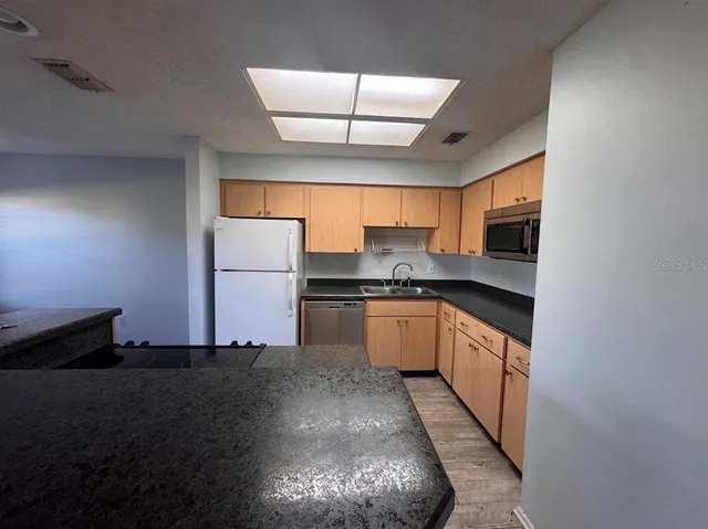 a kitchen with granite countertop a sink a stove and refrigerator