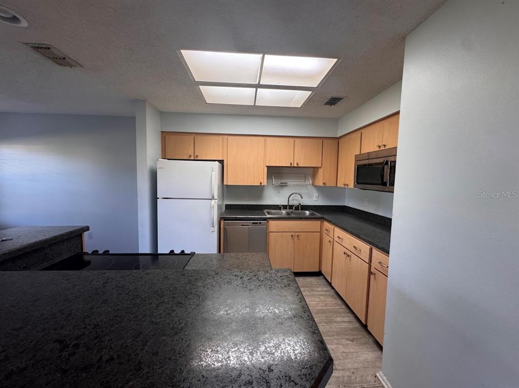 670 Green Valley Road, Unit F9 Palm Harbor, FL 34683 - Photo 5 of 22 a kitchen with granite countertop a sink a stove and refrigerator