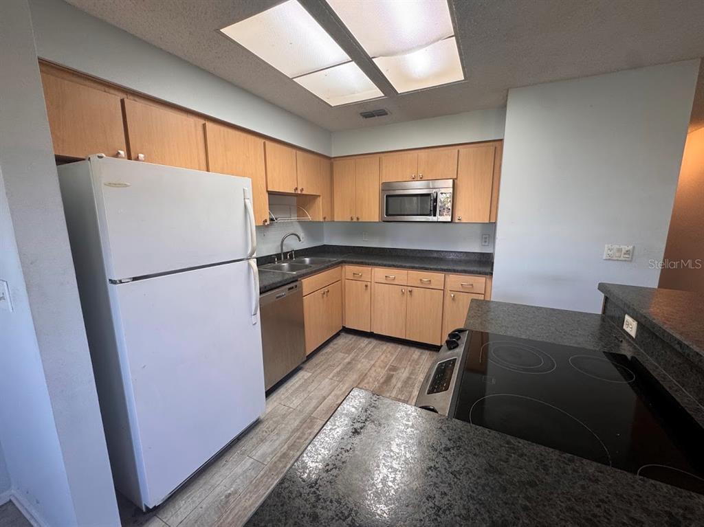 670 Green Valley Road, Unit F9 Palm Harbor, FL 34683 - Photo 8 of 22 a kitchen with stainless steel appliances granite countertop a refrigerator a sink a stove a washer dryer and white cabinets