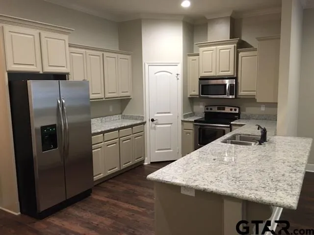 a kitchen with stainless steel appliances granite countertop a refrigerator a sink a stove a microwave and wooden cabinets