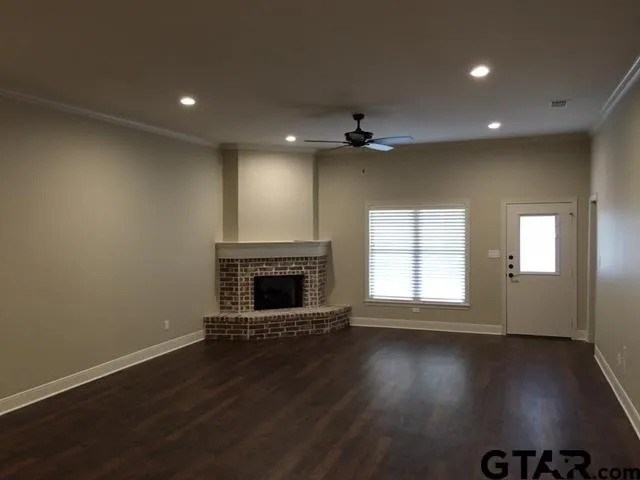 an empty room with wooden floor fireplace and windows