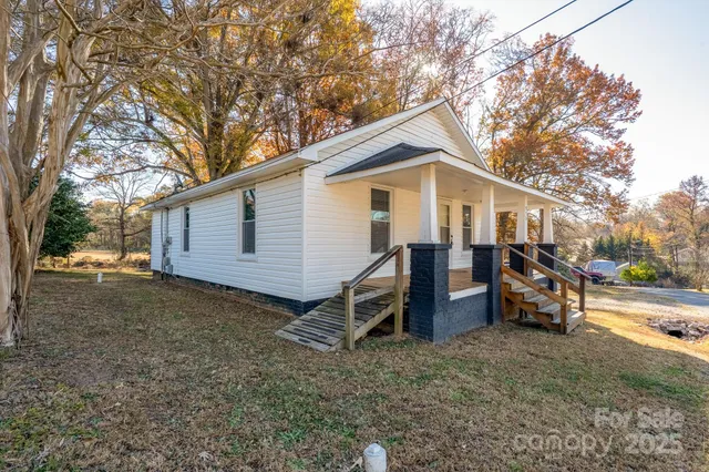 a view of a house with a yard and large trees