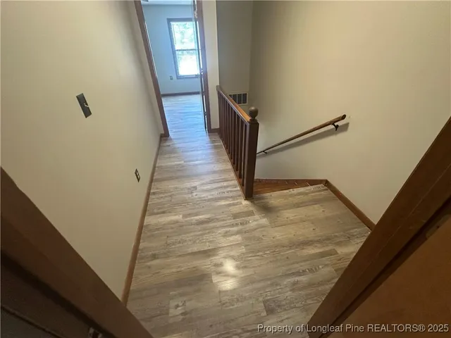 a view of a hallway with wooden floor and staircase
