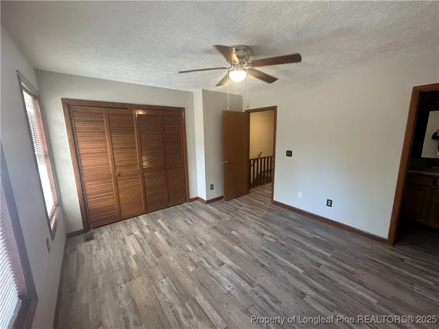 a view of empty room with wooden floor and fan