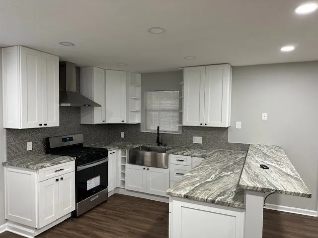 a kitchen with granite countertop a sink a stove and cabinets