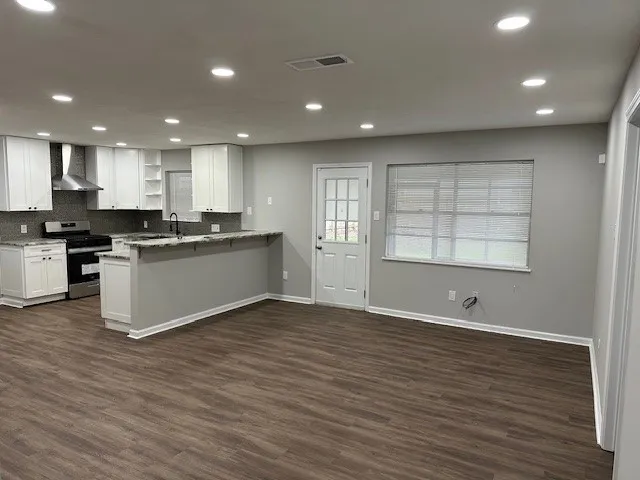 a view of kitchen with kitchen island wooden floors stainless steel appliances and window
