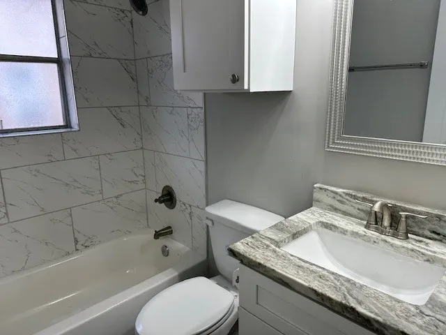 a bathroom with a granite countertop toilet a sink and bathtub