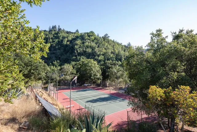 a view of a tennis ground with large trees