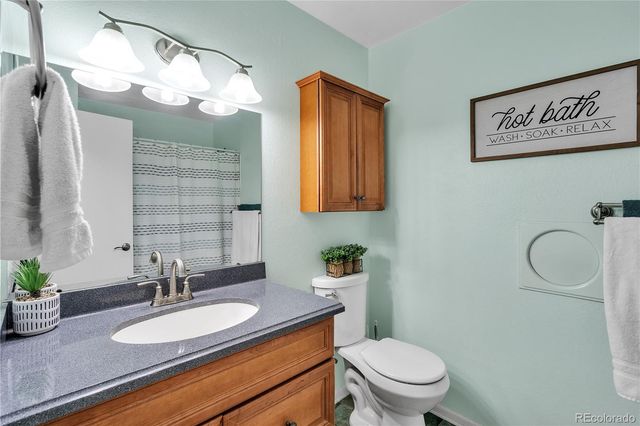 a bathroom with a granite countertop toilet sink and mirror