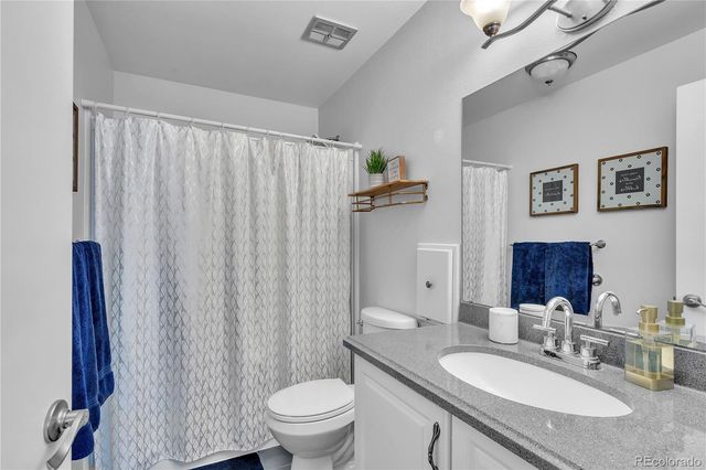 a bathroom with a granite countertop sink a toilet and a mirror