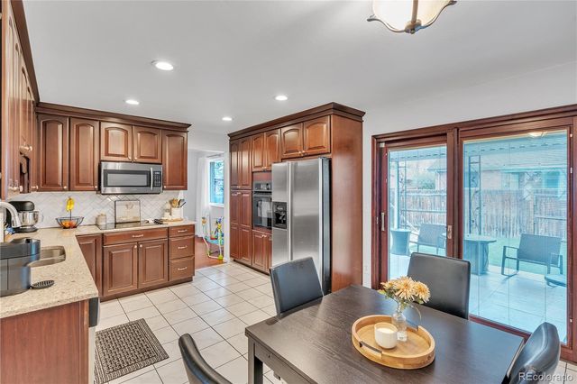 a kitchen with stainless steel appliances granite countertop a stove a refrigerator a sink a dining table and chairs with wooden floor