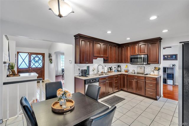 a kitchen with stainless steel appliances granite countertop a stove top oven a sink a dining table and chairs with wooden floor