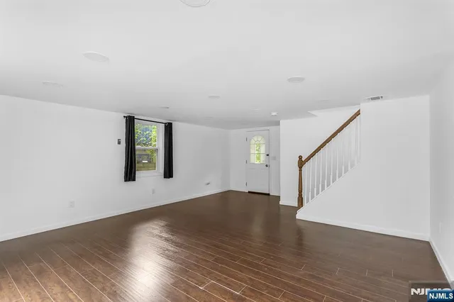 a view of an empty room with wooden floor and windows