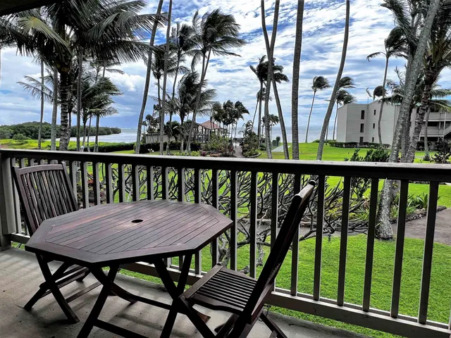 a view of a wooden chairs and table in the balcony