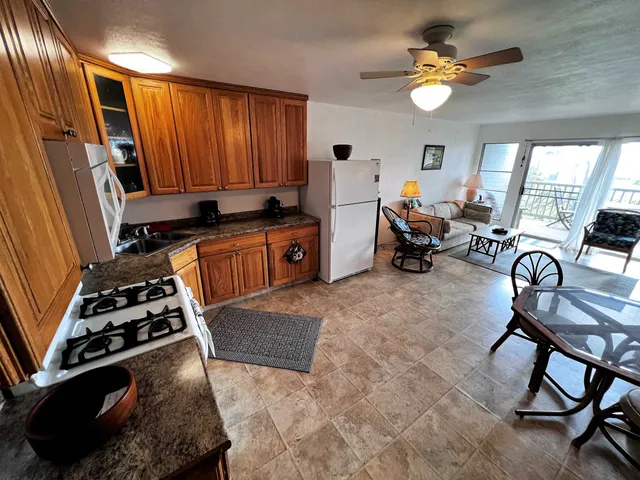 a kitchen with stainless steel appliances granite countertop a stove a sink dishwasher a dining table and chair with the bookshelf