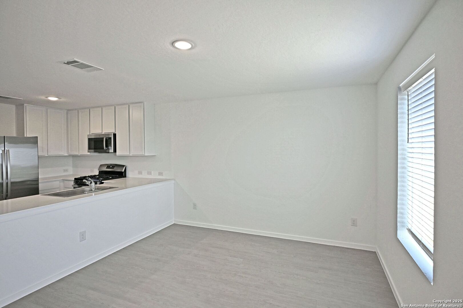 5014 Winecup Cove Converse, TX 78109 - Photo 8 of 25 a kitchen with stainless steel appliances a sink a stove a refrigerator white cabinets and a window