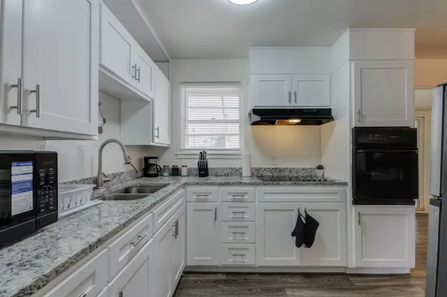 a kitchen with granite countertop white cabinets and white appliances