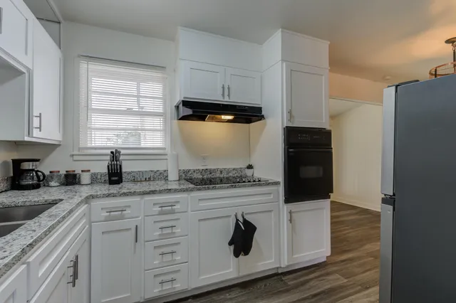 a kitchen with granite countertop white cabinets and white appliances