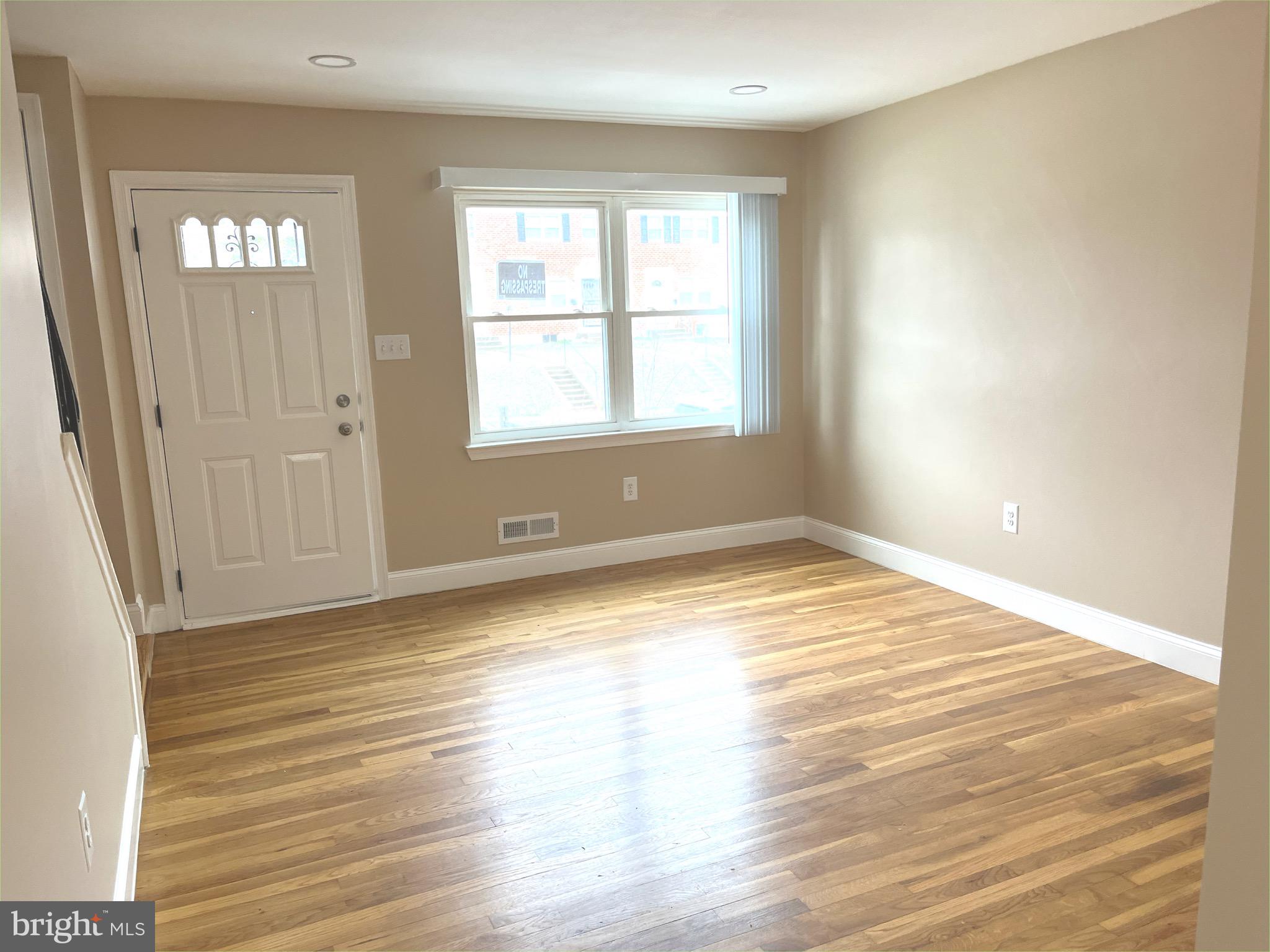 4865 Melbourne Road Baltimore, MD 21229 - Photo 6 of 19 an empty room with wooden floor and windows
