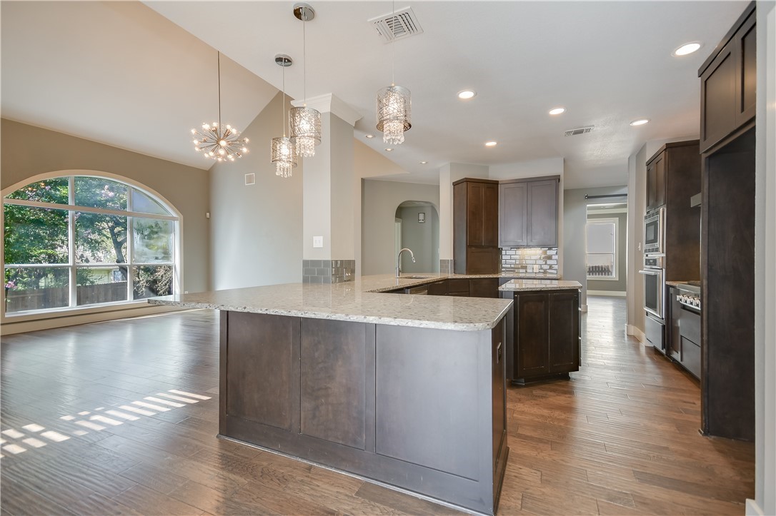 a large kitchen with kitchen island a large counter top space a sink stainless steel appliances and cabinets