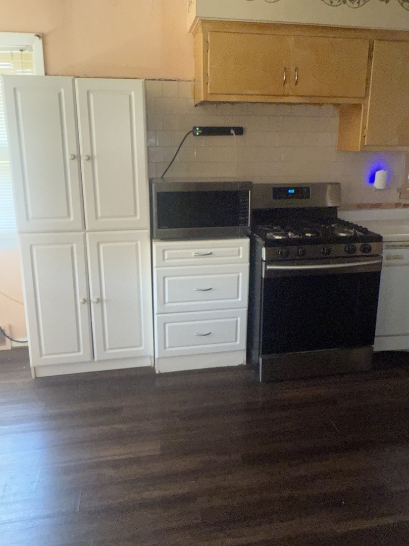 10553 South Calumet Avenue Chicago, IL 60628 - Photo 20 of 21 a kitchen with wooden cabinets and a stove top oven