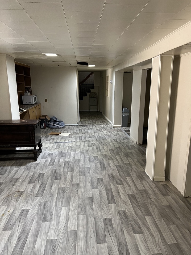 10553 South Calumet Avenue Chicago, IL 60628 - Photo 9 of 21 a view of empty room with wooden floor and stairs