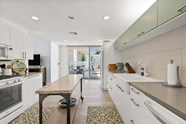 a large kitchen with stainless steel appliances granite countertop a sink dishwasher stove refrigerator and cabinets with wooden floor