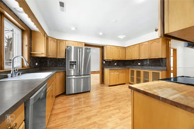 a kitchen with stainless steel appliances granite countertop a sink a stove and refrigerator